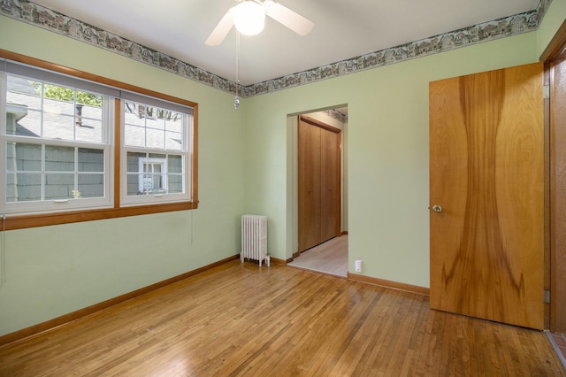 805 E Filer St, Ludington, MI 49431 - unfurnished room with radiator, light wood finished floors, baseboards, and a ceiling fan