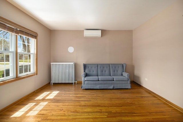 805 E Filer St, Ludington, MI 49431 - sitting room featuring radiator, a wall unit AC, light wood-style floors, and baseboards