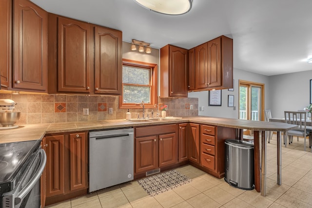 17035 Weber Rd, Holly, MI 48442 - kitchen with appliances with stainless steel finishes, a sink, a peninsula, backsplash, and brown cabinetry