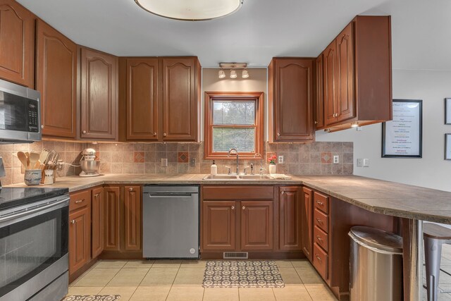 17035 Weber Rd, Holly, MI 48442 - kitchen featuring appliances with stainless steel finishes, a sink, a peninsula, backsplash, and light tile patterned floors