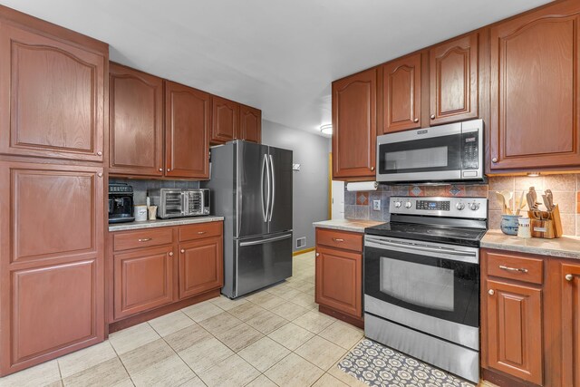 17035 Weber Rd, Holly, MI 48442 - kitchen featuring stainless steel appliances, light countertops, backsplash, light tile patterned flooring, and brown cabinetry