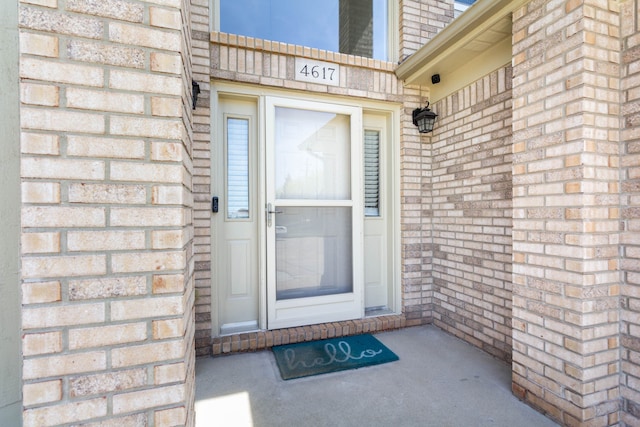 view of exterior entry featuring brick siding