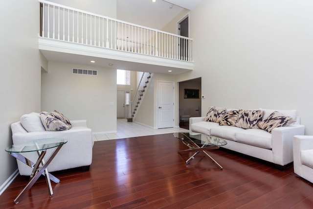 living room with stairs, wood finished floors, baseboards, and a high ceiling