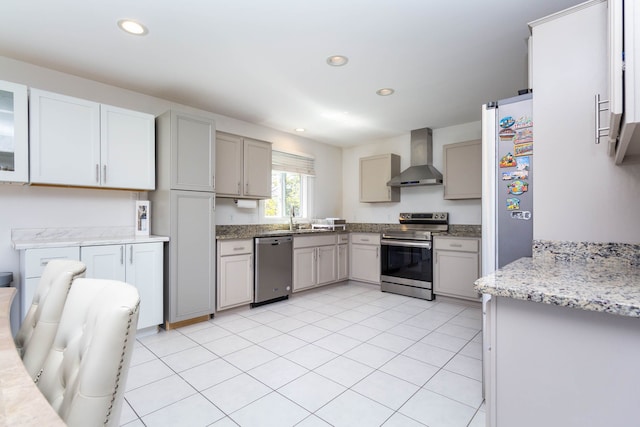kitchen with appliances with stainless steel finishes, wall chimney exhaust hood, a sink, gray cabinetry, and recessed lighting
