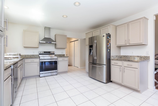 kitchen featuring appliances with stainless steel finishes, wall chimney exhaust hood, recessed lighting, light stone counters, and light tile patterned flooring