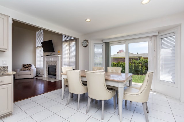 dining space with a tile fireplace, recessed lighting, and light tile patterned floors