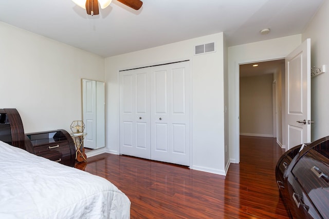 bedroom featuring dark wood-style flooring, baseboards, ceiling fan, and a closet