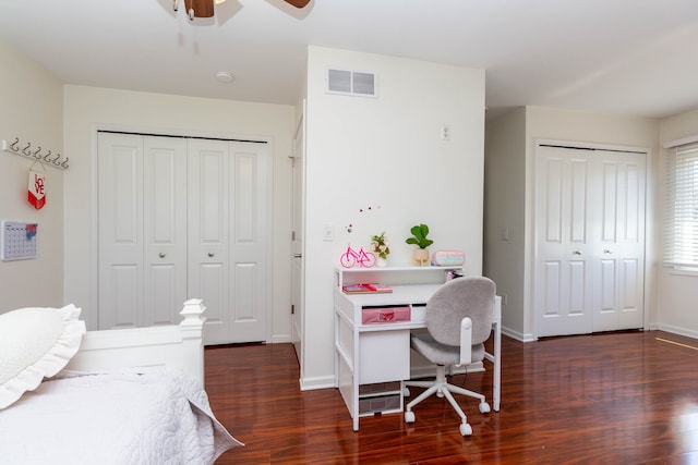 bedroom featuring wood finished floors, baseboards, ceiling fan, and multiple closets