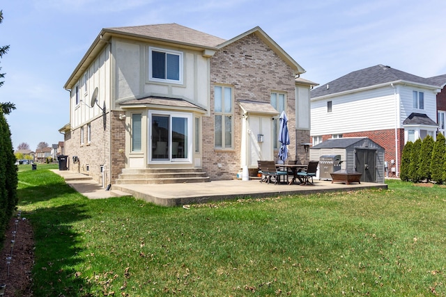 back of house featuring entry steps, a storage unit, brick siding, an outbuilding, and a lawn
