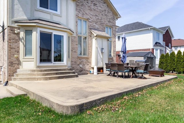 rear view of house with entry steps, brick siding, and a patio area