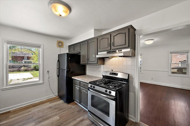 5921 Hillcrest St, Grosse Pointe, MI 48236 - kitchen featuring stainless steel gas range oven, under cabinet range hood, freestanding refrigerator, wood finished floors, and baseboards