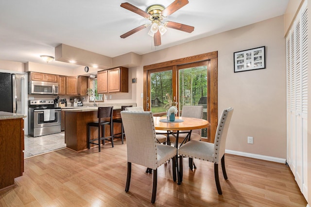 13195 Rainbow Dr, Gregory, MI 48137 - dining area featuring light wood-style flooring, a ceiling fan, and baseboards