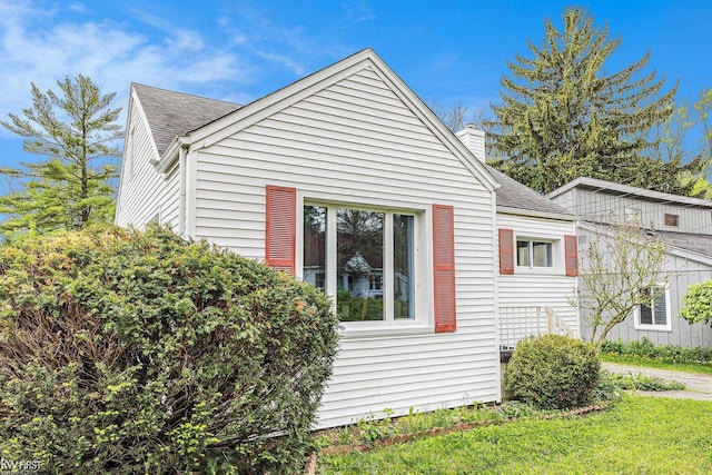 1566 Snyder Rd, East Lansing, MI 48823 - view of property exterior with a shingled roof, a chimney, and a lawn