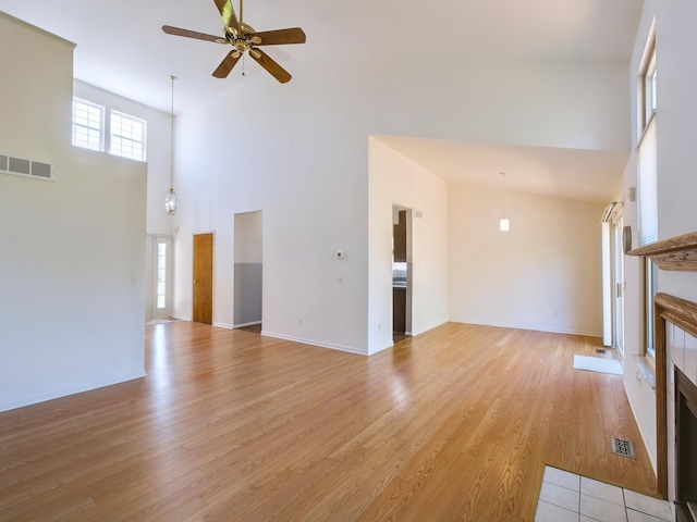 3201 Kilburn Park Cir, Ann Arbor, MI 48105 - unfurnished living room with high vaulted ceiling, ceiling fan, a tile fireplace, light wood-style floors, and baseboards