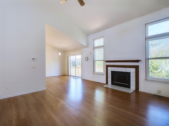 3201 Kilburn Park Cir, Ann Arbor, MI 48105 - unfurnished living room featuring wood finished floors, lofted ceiling, ceiling fan, a tiled fireplace, and baseboards