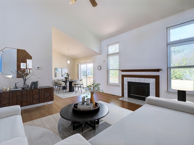3201 Kilburn Park Cir, Ann Arbor, MI 48105 - living area featuring wood finished floors, a ceiling fan, a tiled fireplace, and high vaulted ceiling