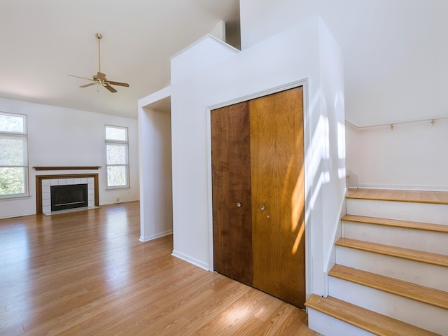 3201 Kilburn Park Cir, Ann Arbor, MI 48105 - stairway with ceiling fan, wood finished floors, vaulted ceiling, a tiled fireplace, and baseboards
