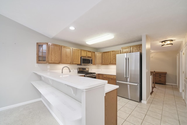 1972 Pine Ridge Dr, Manistee, MI 49660 - kitchen with appliances with stainless steel finishes, a peninsula, light countertops, a kitchen breakfast bar, and baseboards