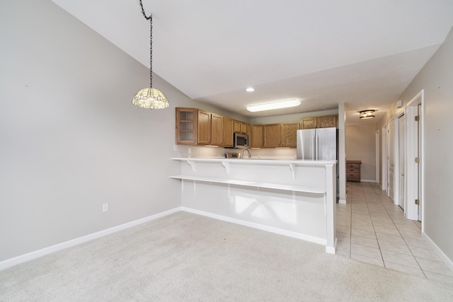 1972 Pine Ridge Dr, Manistee, MI 49660 - kitchen with appliances with stainless steel finishes, a peninsula, a breakfast bar area, light countertops, and brown cabinetry