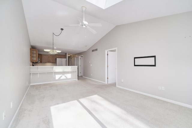 1972 Pine Ridge Dr, Manistee, MI 49660 - unfurnished living room with light colored carpet, a ceiling fan, baseboards, a skylight, and high vaulted ceiling