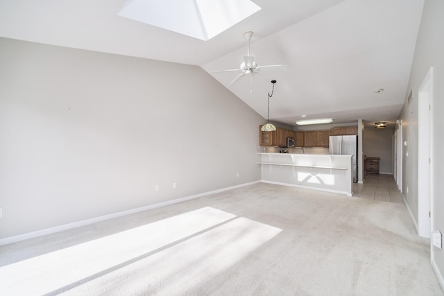1972 Pine Ridge Dr, Manistee, MI 49660 - unfurnished living room featuring light carpet, a skylight, vaulted ceiling, baseboards, and a ceiling fan