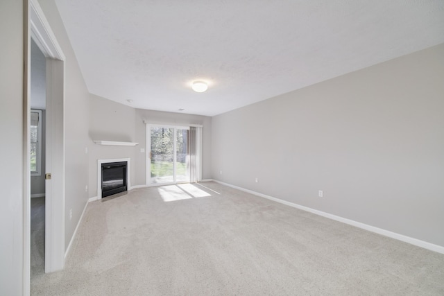 1972 Pine Ridge Dr, Manistee, MI 49660 - unfurnished living room featuring carpet floors, a glass covered fireplace, and baseboards