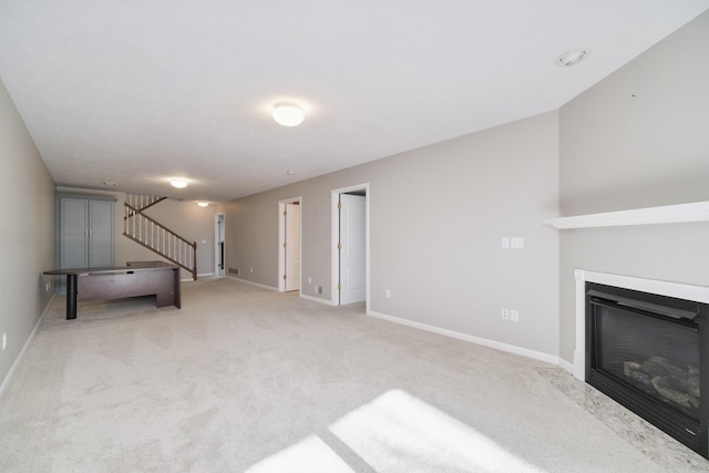 1972 Pine Ridge Dr, Manistee, MI 49660 - unfurnished living room with light carpet, a glass covered fireplace, stairs, and baseboards