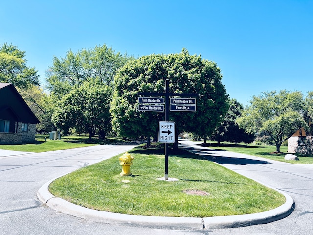 view of asphalt street featuring curbs and traffic signs