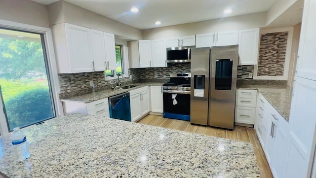 kitchen with stainless steel appliances, a sink, white cabinetry, light stone countertops, and recessed lighting