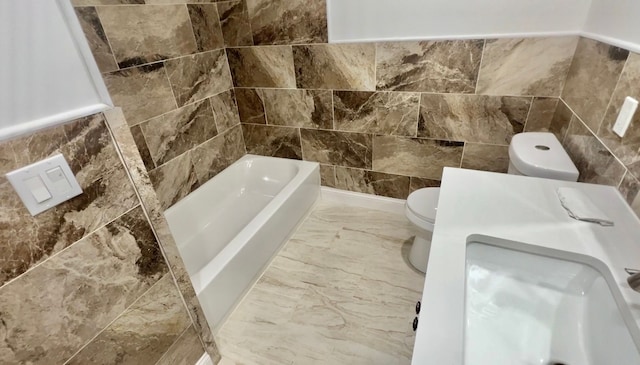 bathroom with a bath, toilet, tile walls, and marble finish floors