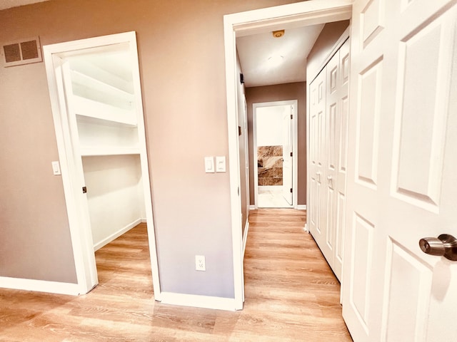 corridor featuring baseboards and light wood-style flooring
