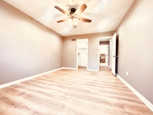 unfurnished bedroom featuring light wood-type flooring, baseboards, ceiling fan, and a spacious closet