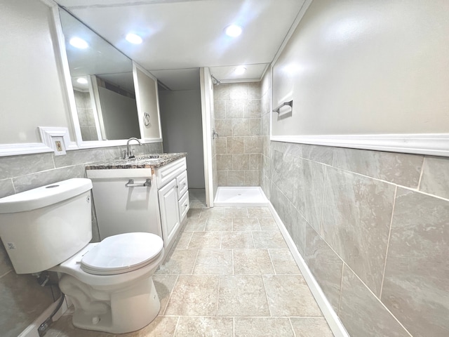 full bathroom with tile walls, recessed lighting, a tile shower, toilet, and vanity