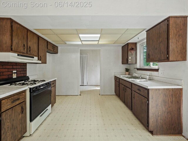 43667 Dequindre Rd, Troy, MI 48085 - kitchen featuring under cabinet range hood, range with gas stovetop, a drop ceiling, light countertops, and light flooring