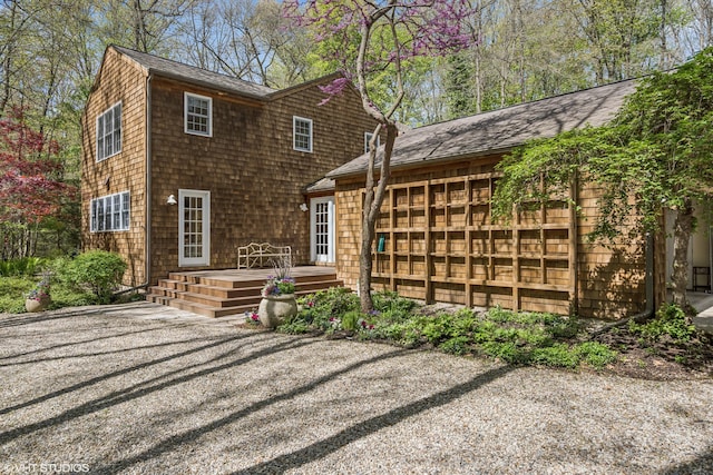 rear view of house featuring a wooden deck and roof with shingles