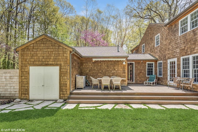 rear view of property featuring a deck, outdoor dining space, and a shingled roof