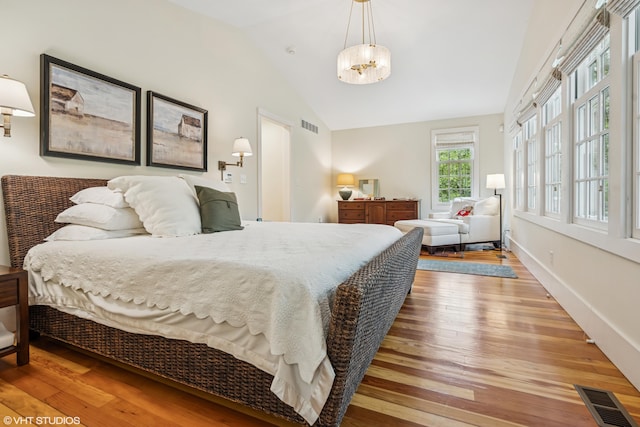 bedroom with wood-type flooring, lofted ceiling, a chandelier, and baseboards