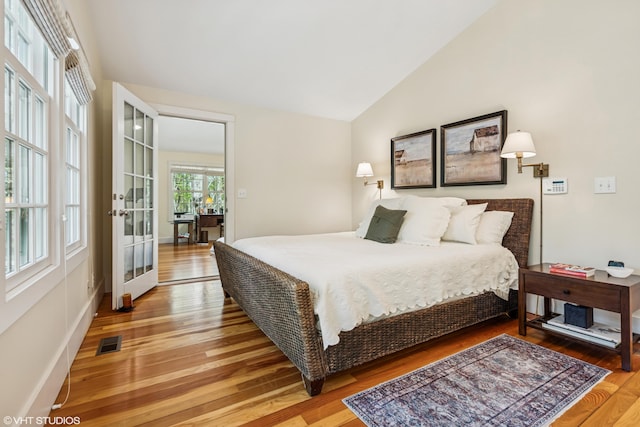 bedroom featuring light wood-style floors, lofted ceiling, and baseboards