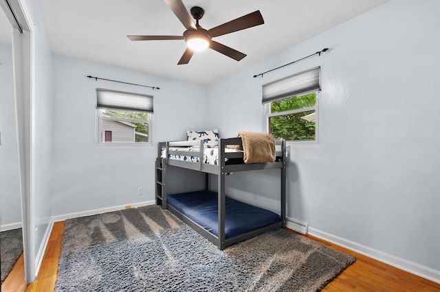 bedroom featuring wood finished floors, multiple windows, and baseboards