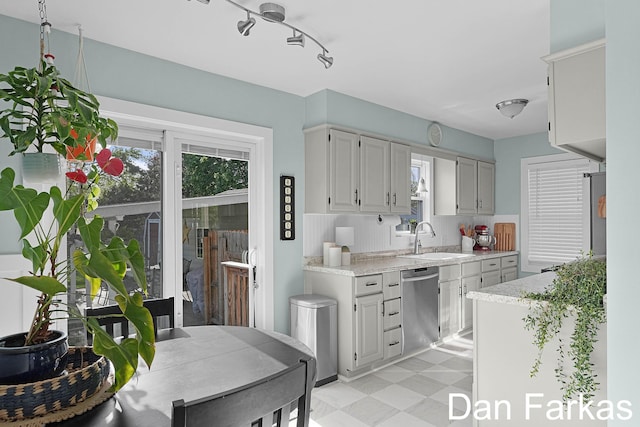 kitchen featuring dishwasher, a sink, healthy amount of natural light, and light flooring