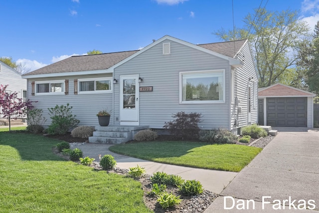 bungalow with a shingled roof, an outbuilding, concrete driveway, and a garage