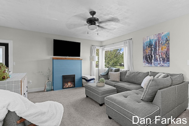 carpeted living room with a ceiling fan, a tiled fireplace, and baseboards