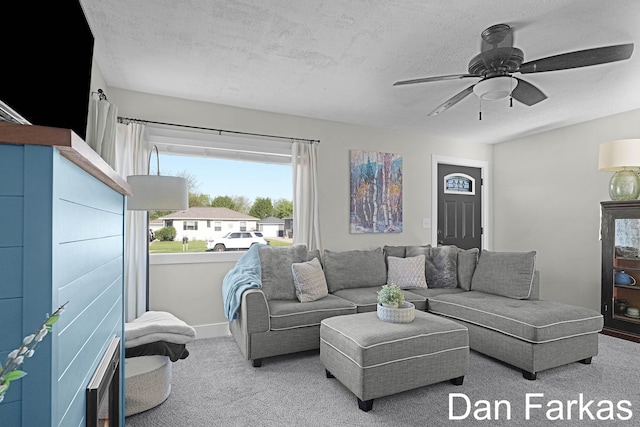 carpeted living room featuring a ceiling fan, a textured ceiling, and baseboards