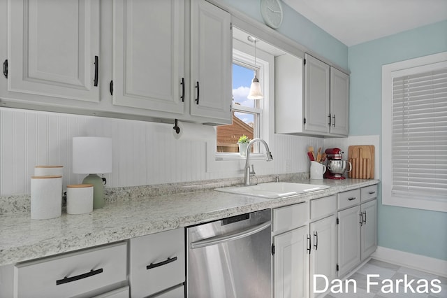 kitchen featuring dishwasher, a sink, hanging light fixtures, and white cabinetry