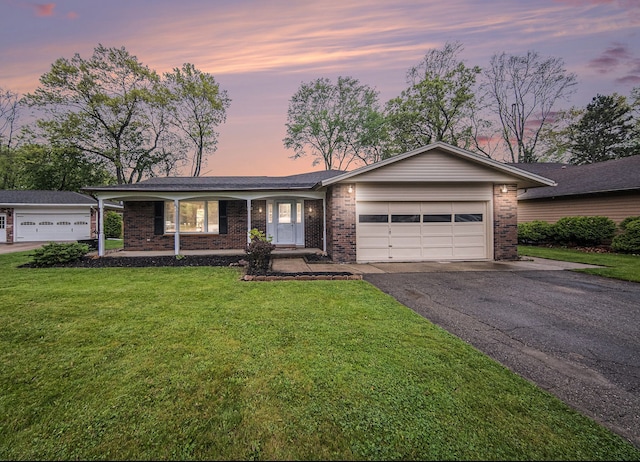 ranch-style house featuring brick siding, asphalt driveway, an attached garage, and a lawn