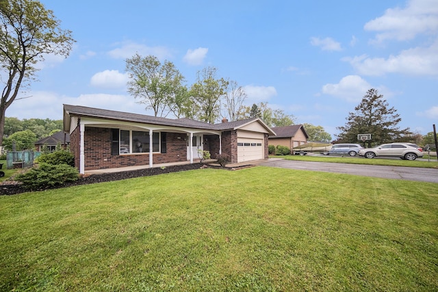 ranch-style home with asphalt driveway, a garage, brick siding, and a front lawn