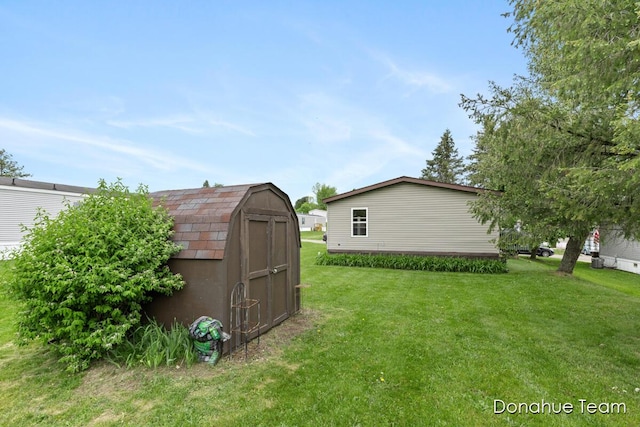 view of green lawn featuring a storage unit and an outbuilding