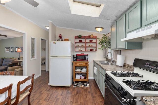 kitchen featuring freestanding refrigerator, range with gas cooktop, a sink, under cabinet range hood, and a ceiling fan