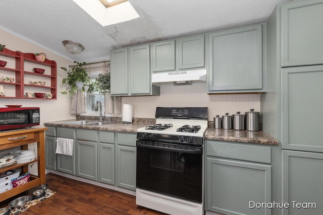 kitchen featuring gas range, under cabinet range hood, a skylight, gray cabinetry, and a textured ceiling