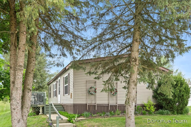 view of side of home with a wooden deck, a lawn, and stairway
